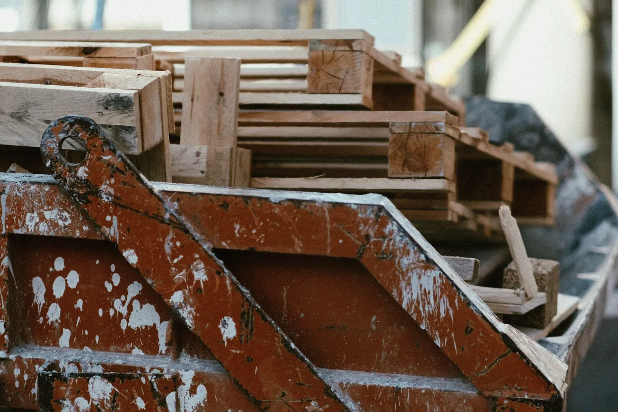 A construction skip filled with broken pallets and renovation debris